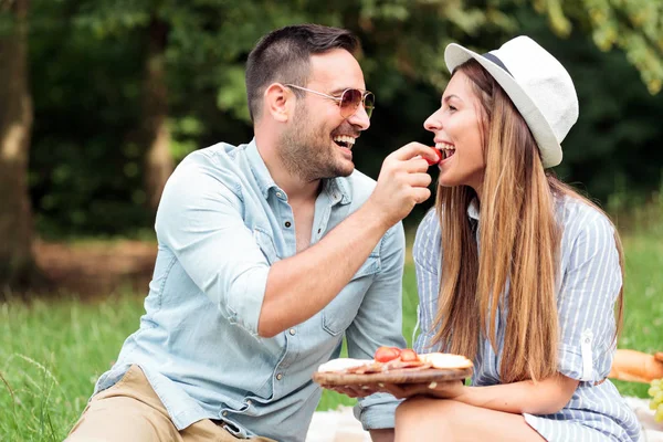 Amar a la joven pareja disfrutando de su tiempo en un parque, teniendo un picnic romántico casual — Foto de Stock