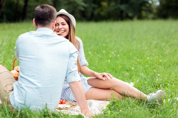 幸福的年轻夫妇在公园里玩得很开心，坐在野餐毯上 — 图库照片