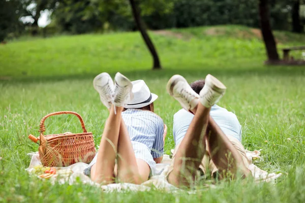 Pareja joven disfrutando de un relajante tiempo de picnic en un parque, acostada en una manta de picnic — Foto de Stock