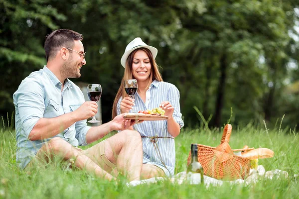 Hermosa pareja joven disfrutando de un romántico picnic en un parque —  Fotos de Stock