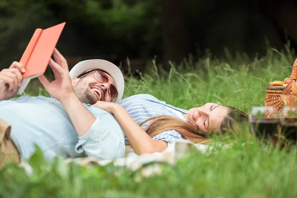 Feliz joven pareja sonriente relajándose en un parque. Acostado en una manta de picnic — Foto de Stock