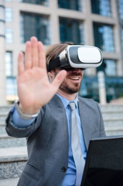 Bir ofis binasının önünde VR gözlük kullanarak genç bir işadamı yakın. Seçici odak kavramı, kafa odaklanmak