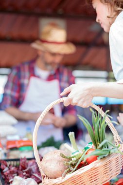 Taze organik sebzelerle dolu bir alışveriş sepeti tutan bir kadının elinin yakın çekim