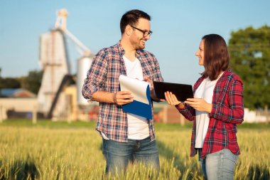 İki mutlu genç erkek ve kadın çiftçiler veya tarım salamı hasat önce bir buğday tarlası teftiş