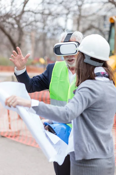 Arquitecto senior serio o hombre de negocios usando gafas de realidad virtual para visualizar el proyecto de construcción en un sitio de construcción — Foto de Stock