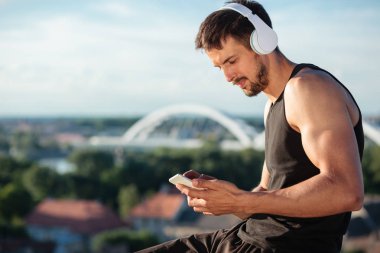 Bir egzersiz sonrası müzik dinleme, akıllı telefon kullanarak kararlı uyum genç adam