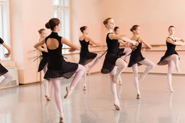 中等组身着黑色礼服的少女在大型舞蹈工作室练习芭蕾动作 — 图库照片