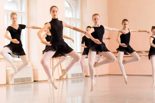 Grupo médio de meninas adolescentes praticando balé se move em um grande estúdio de dança — Fotografia de Stock