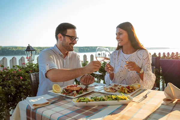 Όμορφο ευτυχισμένο νεαρό ζευγάρι κάνει μια πρόποση, γιορτάζοντας την επέτειο ή τα γενέθλια σε ένα εστιατόριο — Φωτογραφία Αρχείου