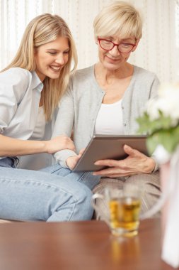Kıdemli anne ve kızı bir tablet üzerinde internette tarama