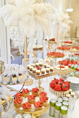 Zarif bir düğün resepsiyonunda zengin ve güzel dekore edilmiş bir tatlı masası ve pastalar bulunur..