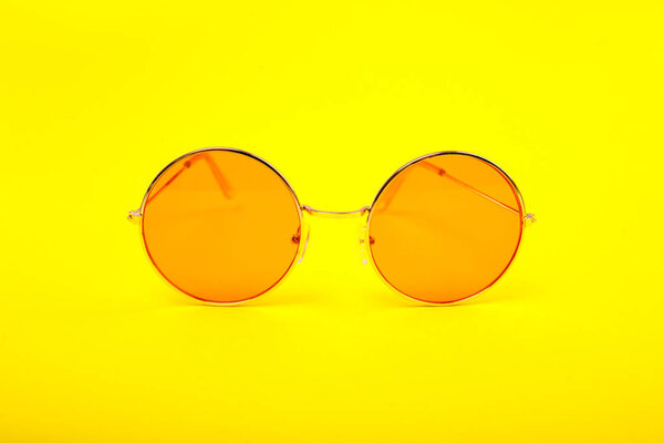 Bright orange glasses on a yellow background.