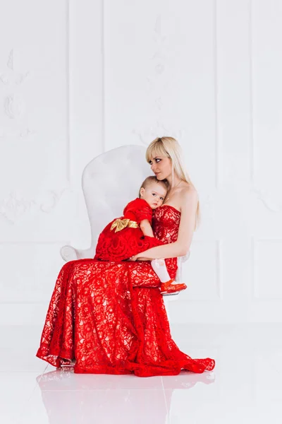 Trevlig, Familj, bra foto av mor och dotter i röda klänningar i studion. Mors dag och döttrar. Annonsera familjevärderingar och traditioner. — Stockfoto