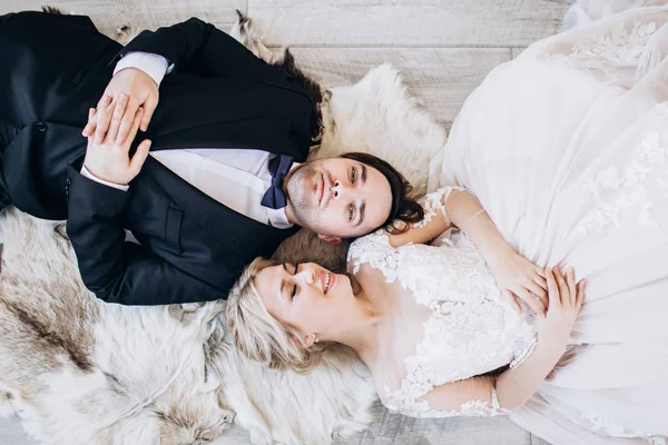 Nevěsta a ženich na svatebních šatech leží na podlaze a usmívají se. — Stock fotografie