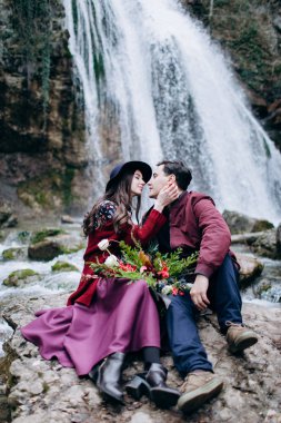 Bir şelale arka planda sevgi dolu, şık, Genç bir çift.