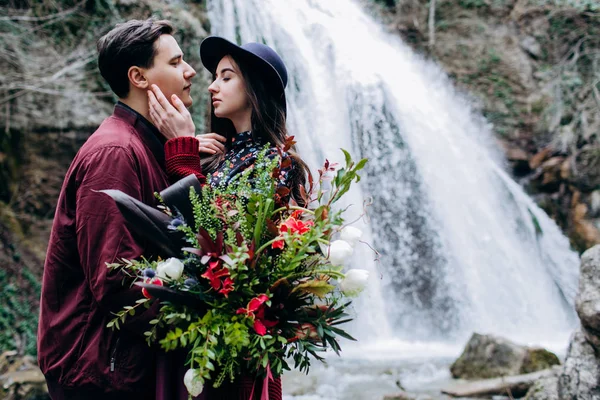 Um casal amoroso, elegante e jovem apaixonado no fundo de uma cachoeira . — Fotografia de Stock