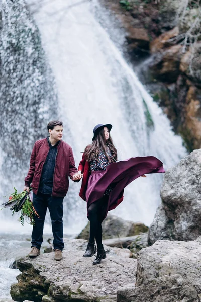 Una pareja amorosa, elegante y joven enamorada en el fondo de una cascada . —  Fotos de Stock