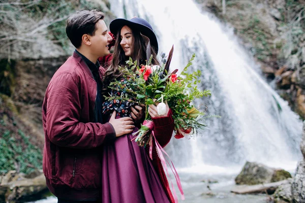 Um casal amoroso, elegante e jovem apaixonado no fundo de uma cachoeira . — Fotografia de Stock