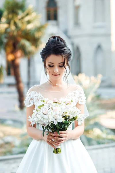 城の背景に白い花の花束を手に花嫁. — ストック写真