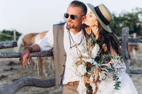 Boho tarzında giyinmiş damat yavaşça gelin öper.