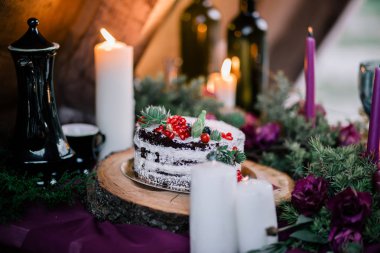 Çiçekler ve mumlarla çevrili narlı ve sulu bir düğün pastası..