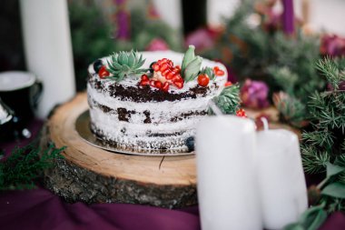 Çiçekler ve mumlarla çevrili narlı ve sulu bir düğün pastası..