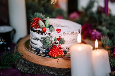 Çiçekler ve mumlarla çevrili narlı ve sulu bir düğün pastası..