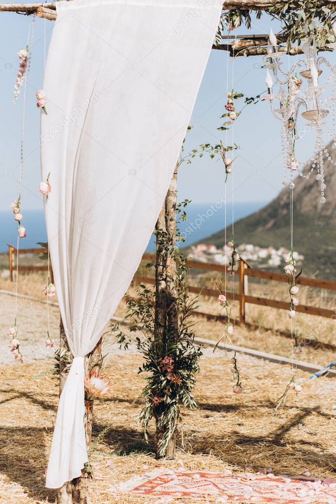 Arch decorated with lively floristics on the background of the sea. Boho style