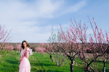 Pembe bir elbise ve makyaj şeftali pembe çiçekli bir bahçede genç kız.
