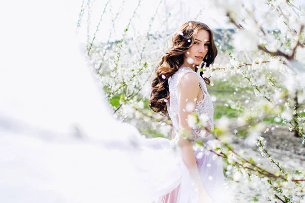 Young girl in a white flowered garden of peaches in a white dress and makeup. — Stock Photo, Image