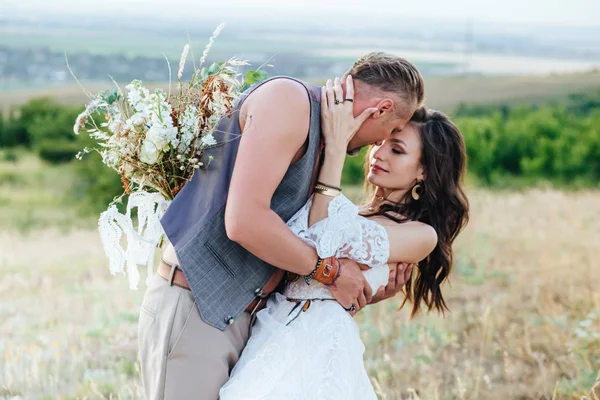 O noivo vestido com o estilo de boho beija suavemente a noiva . — Fotografia de Stock