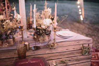 Bordo tabaklar ve taze çiçekler ile ahşap bir masa üzerinde gelin ve damat romantik akşam yemeği. 