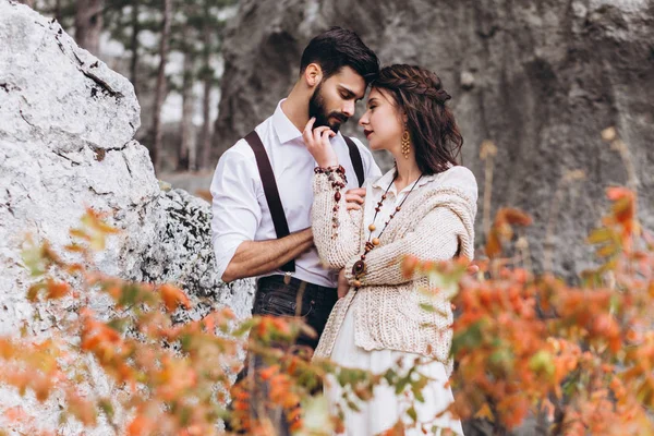 Sakallı şık adam boho tarzında bir elbise giymiş bir kız kucaklar. 