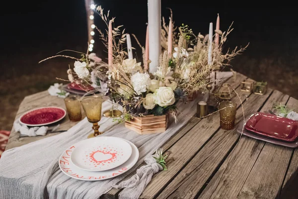 Dîner romantique des mariés sur une table en bois avec assiettes bordeaux et fleurs fraîches . — Photo