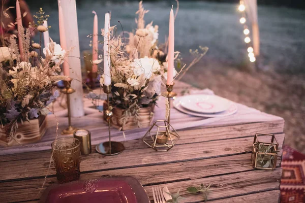 Romantic dinner of the bride and groom on a wooden table with burgundy plates and fresh flowers. — Stock Photo, Image