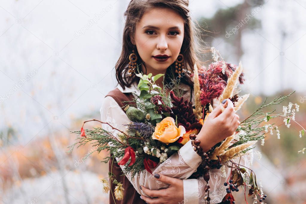 Wedding floristry in a yellow autumn meadow in the hands of a girl dressed in the style of boho.