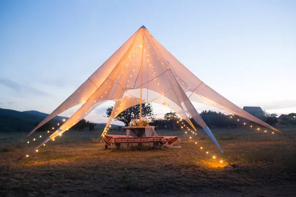 Dekorasyon, çiçek, ışık ile gelin ve damat için açık havada Boho düğün çadırı.