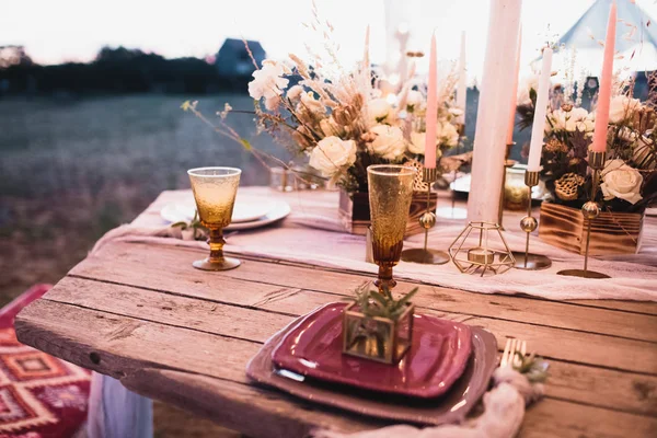 Romantisches Abendessen der Braut und des Bräutigams auf einem Holztisch mit weinroten Tellern und frischen Blumen. — Stockfoto