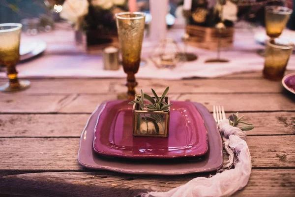 Cena romántica de los novios sobre una mesa de madera con platos borgoña y flores frescas . —  Fotos de Stock