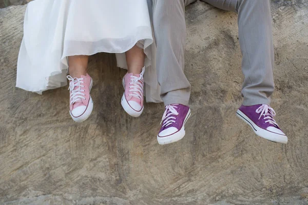 La novia y el novio con zapatillas de deporte púrpura y rosa . — Foto de Stock