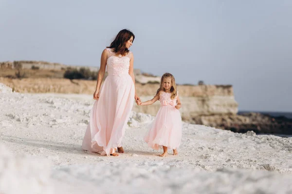Matka a dcera na útesu a podívejte se na moře v růžových šatech. — Stock fotografie