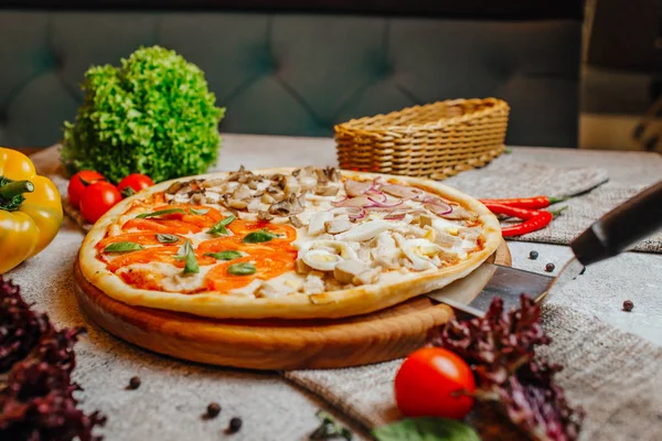 Pizza saborosa fatiada deliciosa com legumes na mesa de madeira . — Fotografia de Stock