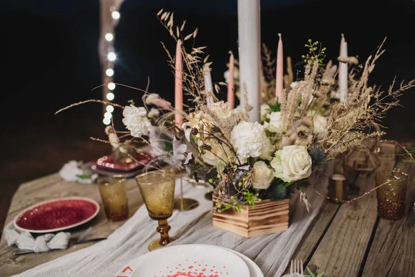 Dîner romantique sur une table en bois avec assiettes bordeaux et fleurs fraîches . — Photo