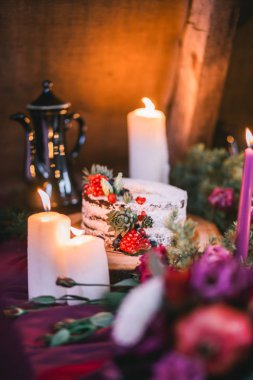 Çiçekler ve mumlarla çevrili narlı ve sulu bir düğün pastası..