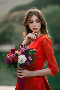 Bir buket nar ve gülle kırmızı elbiseli genç gelin..