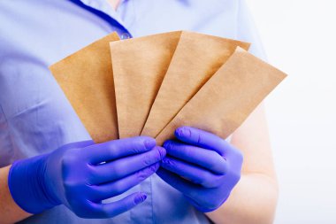 Steril eldivenler giydirilen ellerde aletlerin sterilizasyonu için torbalar.