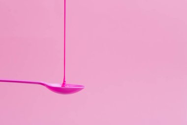 Pembe neon boya pembe bir kaşık üzerine akar.