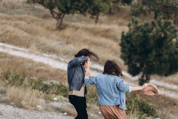 Boyfriend and Girlfriend run in tall yellow grass in the forest.