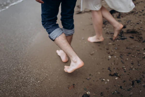 Dos pares de piernas de amantes caminan sobre la arena en la orilla del mar. —  Fotos de Stock
