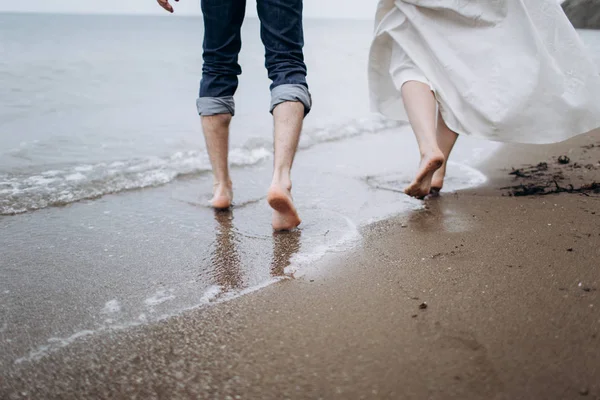 Dois pares de pernas de amantes caminham na areia na praia. — Fotografia de Stock